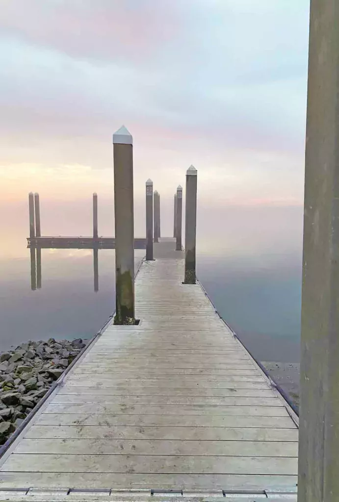 Pier Extending into Pale Blue Cloudy Sky with Water's Reflection, Creating an Illusion of Floating in the Sky
