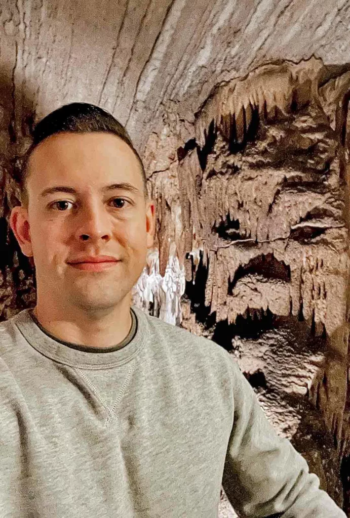 man taking a selfie in front of stalactites that resemble a face in the Bristol Caverns of Tennessee