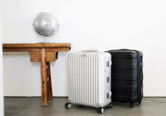 a white and black suitcase packed and ready to travel the world with a table next to it featuring a silver globe
