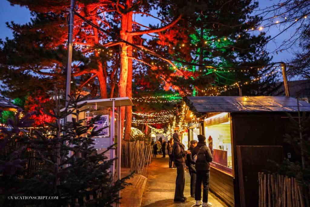 red and green lit up trees behind a christmas market booth