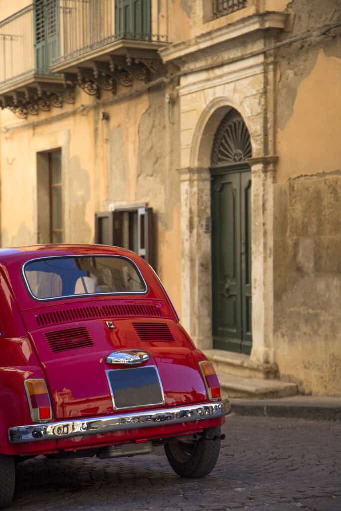 red italian car in Catania, SIcily parked on a cobblestone street near a residence