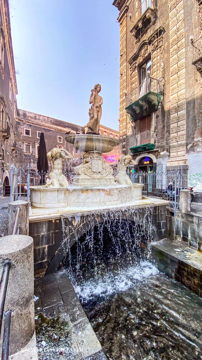 The Amenano Fountain flowing like a cascading sheet of water, positioned in front of the entrance to Catania’s fish market.