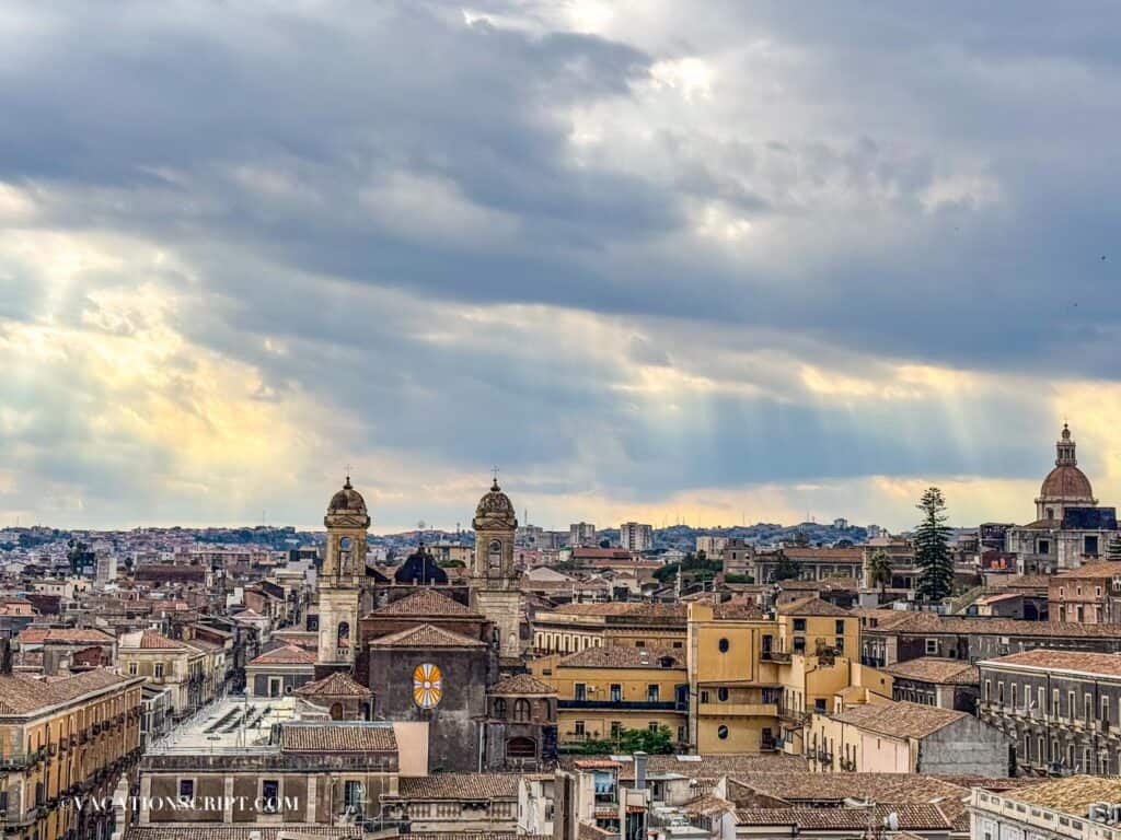 View from the top of the Church of the Abbey of Sant’Agata showing rooftops of buildings and distant churches beneath a vibrant sunset sky.