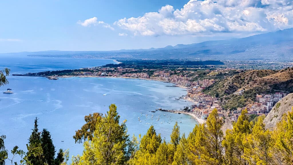 Beautiful things to do in Taormina include seeing this epic view at the top of the town showing the sea and land jutting out with Mt. Etna forming in the background