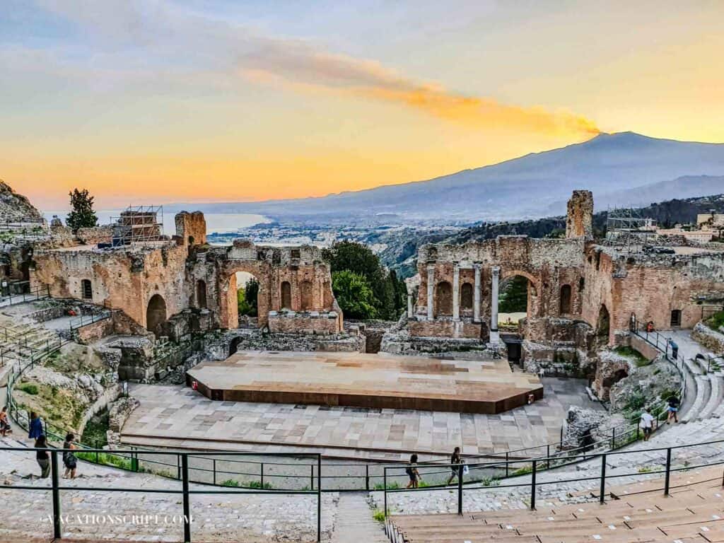 Ancient Greek Theatre in Taormina Sicily with preserved stone stadium seating and view of Mount Etna.